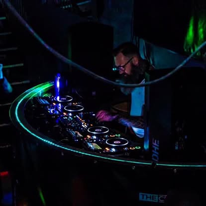A DJ's hands on the decks under green light